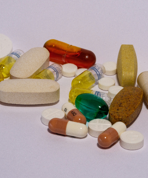 Verschiedene Tabletten und Kapseln in unterschiedlichen Farben und Formen liegen auf einer hellen Oberfläche.