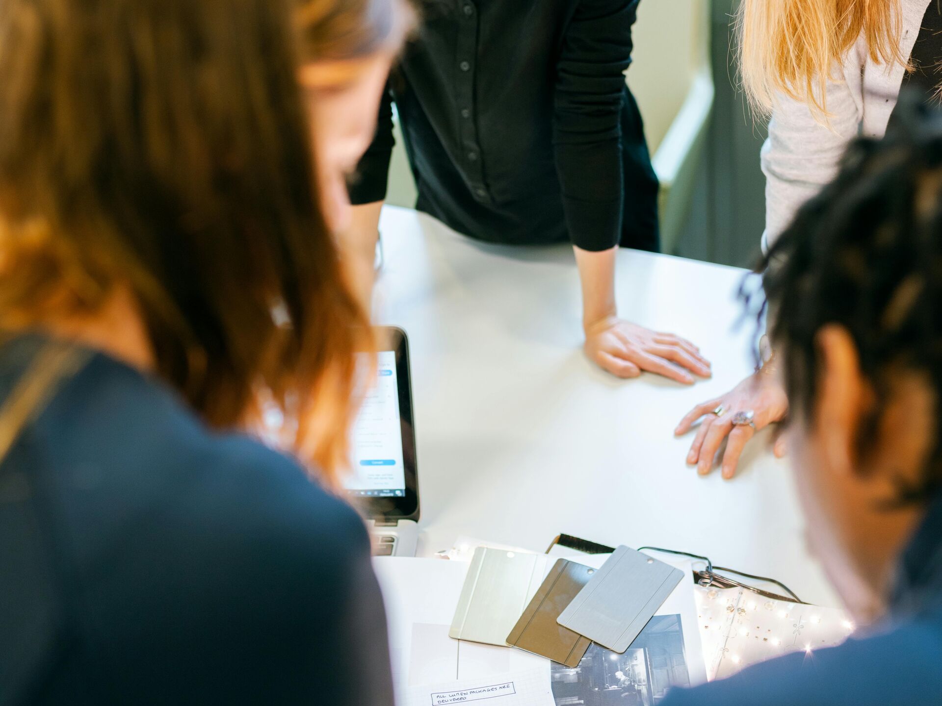 Gruppe von Personen arbeitet gemeinsam an einem Tisch und bespricht Unterlagen in einem hellen Büro.