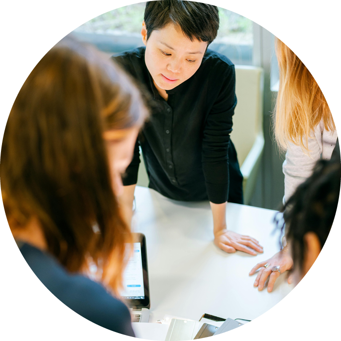 Mehrere Personen stehen um einen Tisch und besprechen gemeinsam Unterlagen in einer modernen Büroumgebung.